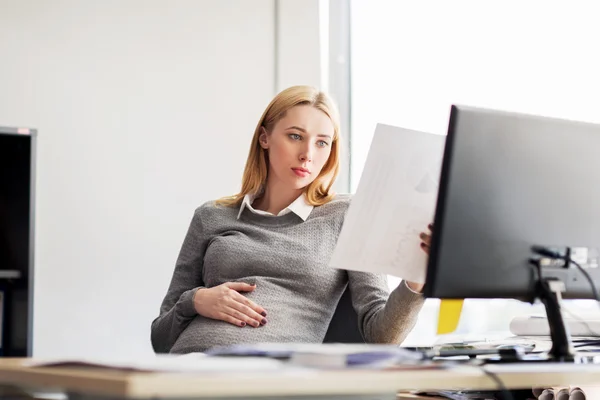 Femme d'affaires enceinte lecture de documents au bureau — Photo