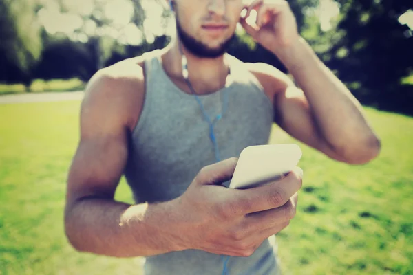 イヤホンと公園でスマート フォンを持つ若者 — ストック写真