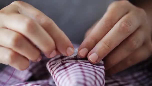 Женщина с шитьем игл на пуговице к рубашке — стоковое видео