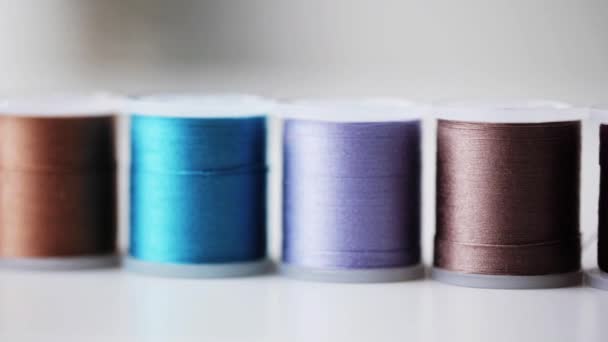 Row of colorful thread spools on table — Stock Video