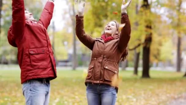 Glückliches junges Paar wirft Herbstblätter in Park — Stockvideo