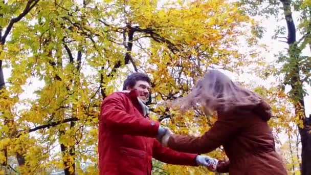 Счастливая молодая пара веселится в осеннем парке — стоковое видео