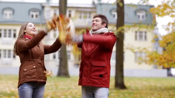 Feliz pareja joven lanzando hojas de otoño en el parque — Vídeos de Stock