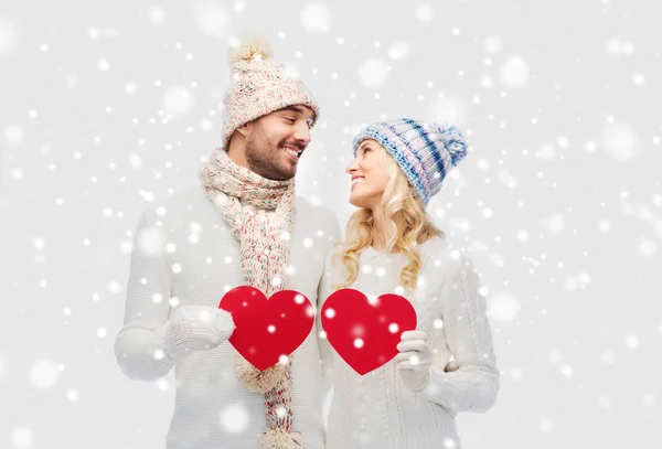 Lächelndes Paar in Winterkleidung mit roten Herzen — Stockfoto