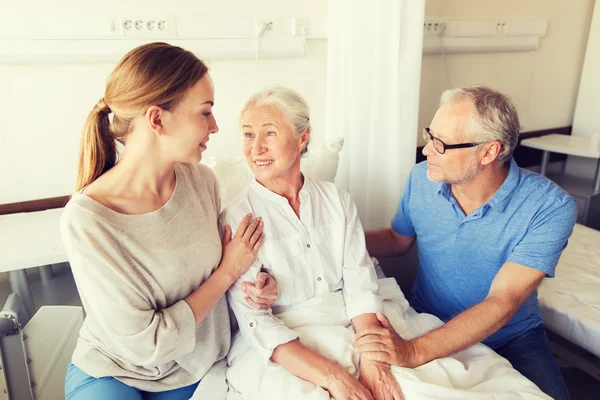 Familia feliz visitando a la mujer mayor en el hospital — Foto de Stock