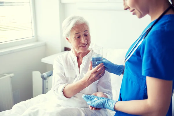 Enfermera que da medicina a una mujer mayor en el hospital — Foto de Stock