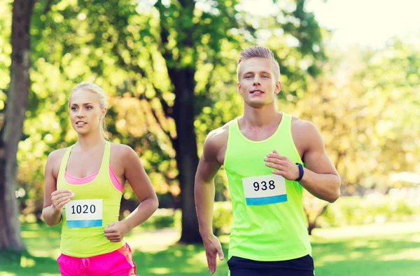 Feliz deportistas pareja carreras ingenio insignia números — Foto de Stock