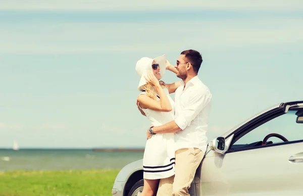 Счастливые мужчина и женщина обнимаются рядом с машиной в море — стоковое фото