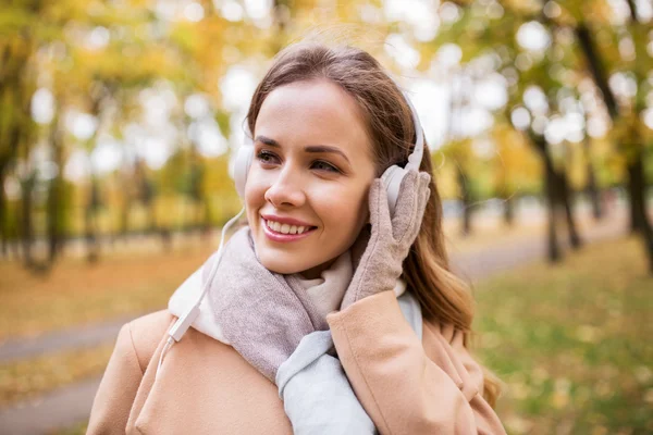 Женщина в наушниках слушает музыку в осеннем парке — стоковое фото