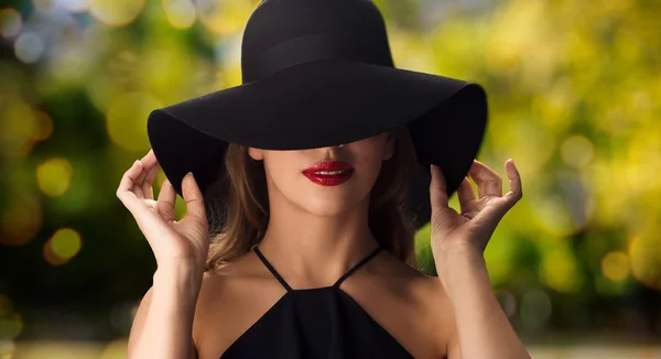 Beautiful woman in black hat over dark background — Stock Photo, Image