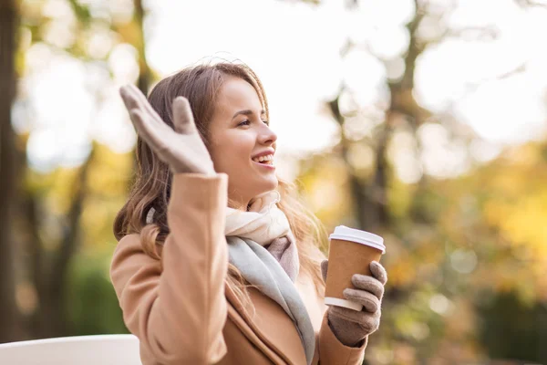 Fröhliche junge Frau trinkt Kaffee im Herbstpark — Stockfoto