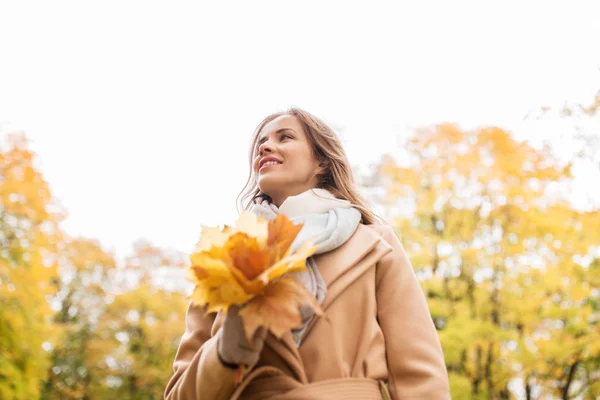 Hermosa mujer con hojas de arce en el parque de otoño — Foto de Stock