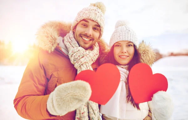Casal feliz com corações vermelhos sobre paisagem de inverno — Fotografia de Stock