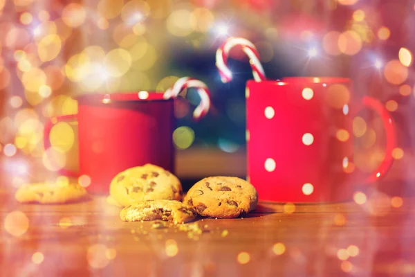 Weihnachtsbonbons und Tassen auf Holztisch — Stockfoto