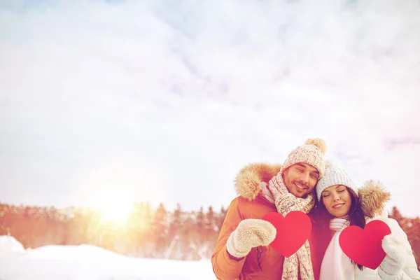 Casal feliz com corações vermelhos sobre paisagem de inverno — Fotografia de Stock