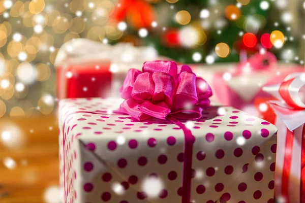 Close up of gift boxes over christmas tree lights — Stock Photo, Image