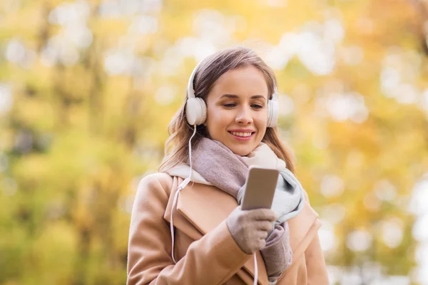 Femme avec smartphone et écouteurs dans le parc d'automne — Photo