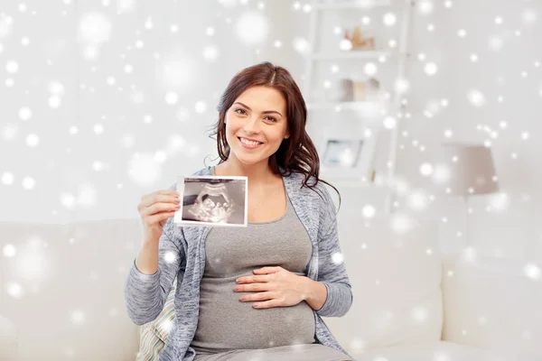 Счастливая беременная женщина с ультразвуком изображения дома — стоковое фото