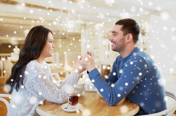 Happy couple with tea holding hands at restaurant — Stock Photo, Image