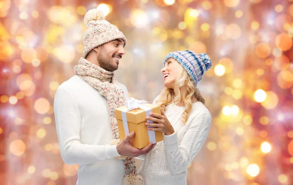 Casal sorridente em roupas de inverno com caixa de presente — Fotografia de Stock