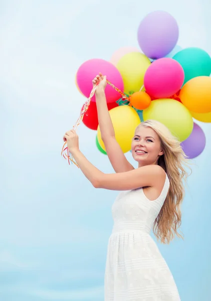 Улыбающаяся женщина с разноцветными воздушными шарами снаружи — стоковое фото