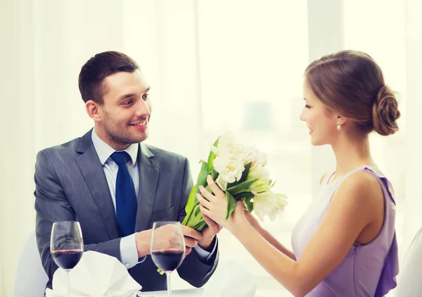 Sorrindo homem dando buquê de flores no restaurante — Fotografia de Stock