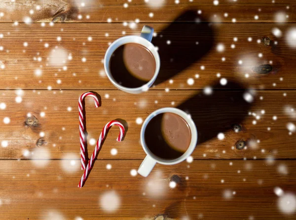 Рождественские конфетки и чашки на деревянном столе — стоковое фото