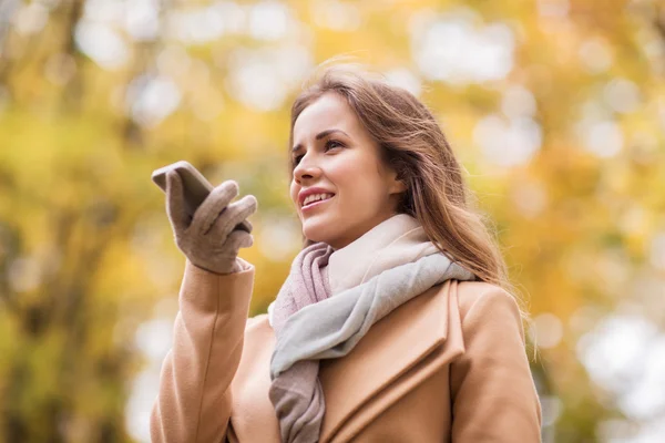 Femme enregistrement de la voix sur smartphone dans le parc d'automne — Photo