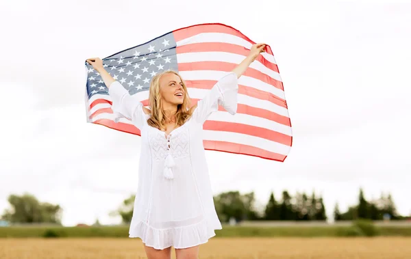 Mulher feliz com bandeira americana no campo de cereais — Fotografia de Stock