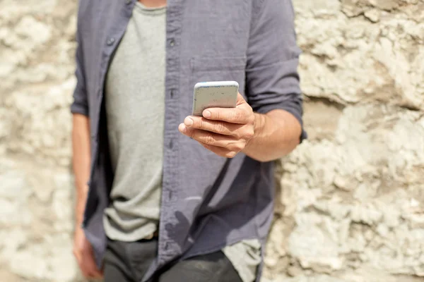Close up of man with smartphone at stone wall — Stock Photo, Image