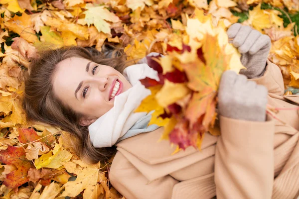 Όμορφη γυναίκα ευτυχισμένη ξαπλωμένος σε φθινοπωρινά φύλλα — Φωτογραφία Αρχείου