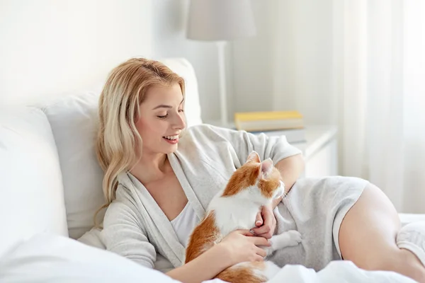 Gelukkig jonge vrouw met kat in bed thuis — Stockfoto