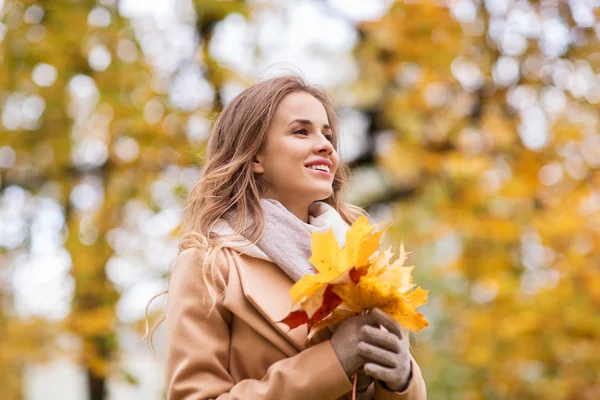 Beautiful woman with maple leaves in autumn park — Stock Photo, Image