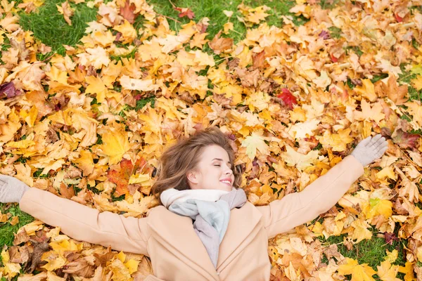 Krásná šťastná žena ležící na podzimní listí — Stock fotografie