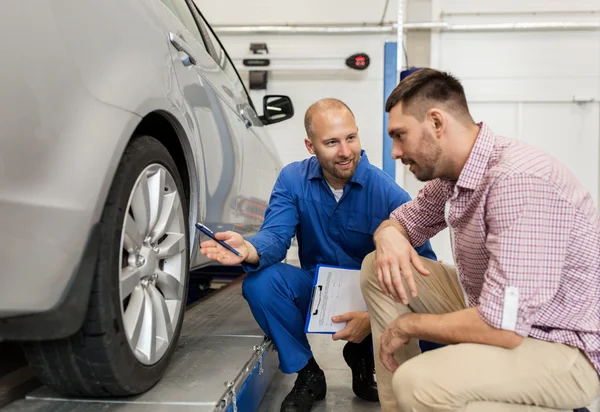 Auto mekaniker med Urklipp och man på bilverkstad — Stockfoto