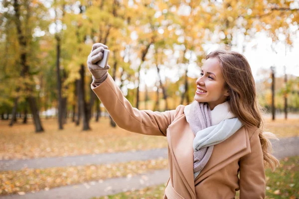 秋の公園でスマート フォンで selfie を取って女性 — ストック写真