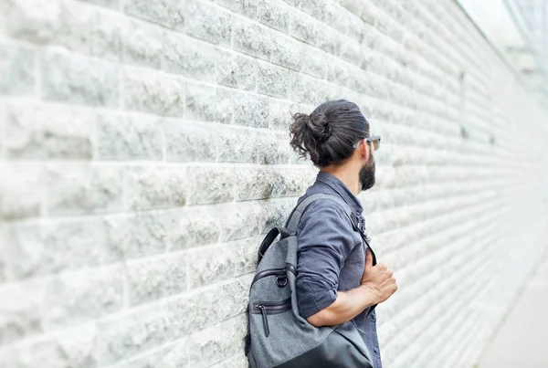 Homem com mochila em pé na parede de rua da cidade — Fotografia de Stock