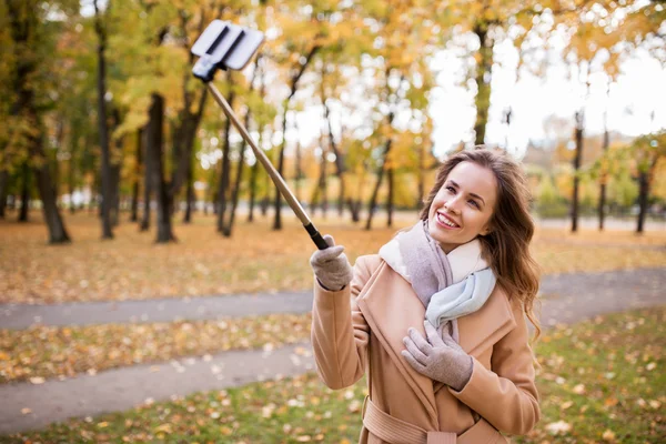 Женщина делает селфи на смартфоне в осеннем парке — стоковое фото