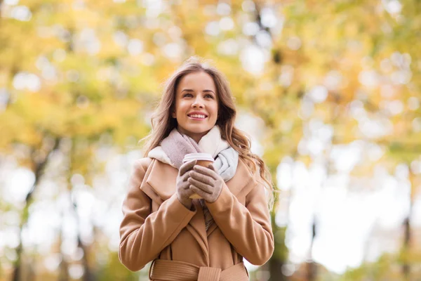 Fröhliche junge Frau trinkt Kaffee im Herbstpark — Stockfoto