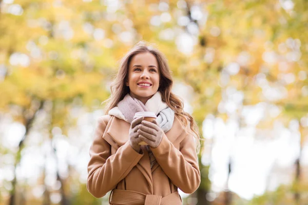 Felice giovane donna che beve caffè nel parco autunnale — Foto Stock