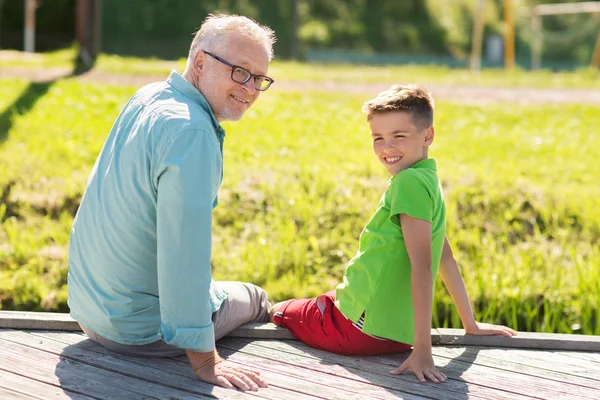 Abuelo y nieto sentado en la litera del río —  Fotos de Stock