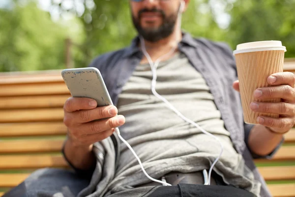 man with earphones and smartphone drinking coffee