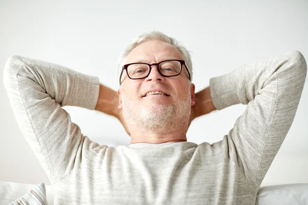 Sorridente homem sênior em óculos relaxante no sofá — Fotografia de Stock