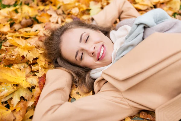 Bela mulher feliz deitada em folhas de outono — Fotografia de Stock
