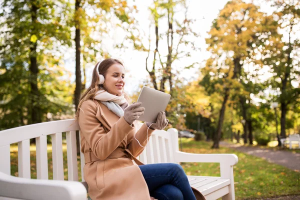 Femme avec tablette PC et écouteurs dans le parc d'automne — Photo