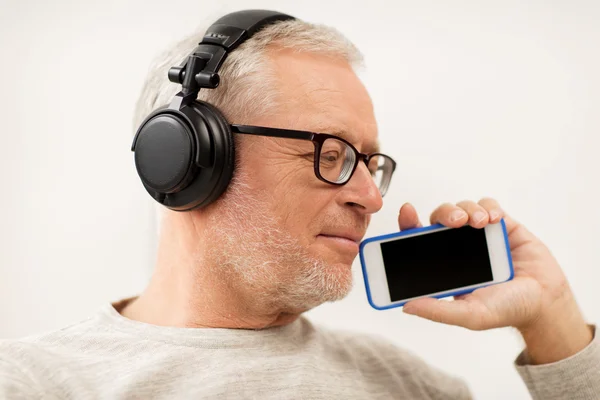 Счастливый пожилой человек со смартфоном и наушниками — стоковое фото