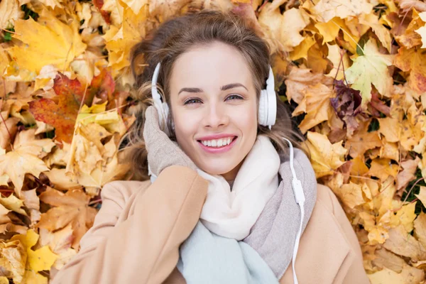 秋で音楽を聴くヘッドフォンを持つ女性 — ストック写真