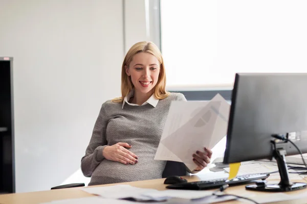 Empresaria embarazada leyendo papeles en la oficina — Foto de Stock