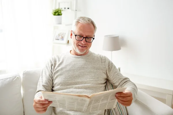 Hombre mayor en gafas leyendo el periódico en casa — Foto de Stock