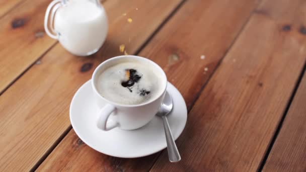 Main laissant tomber le sucre dans une tasse à café sur la table — Video